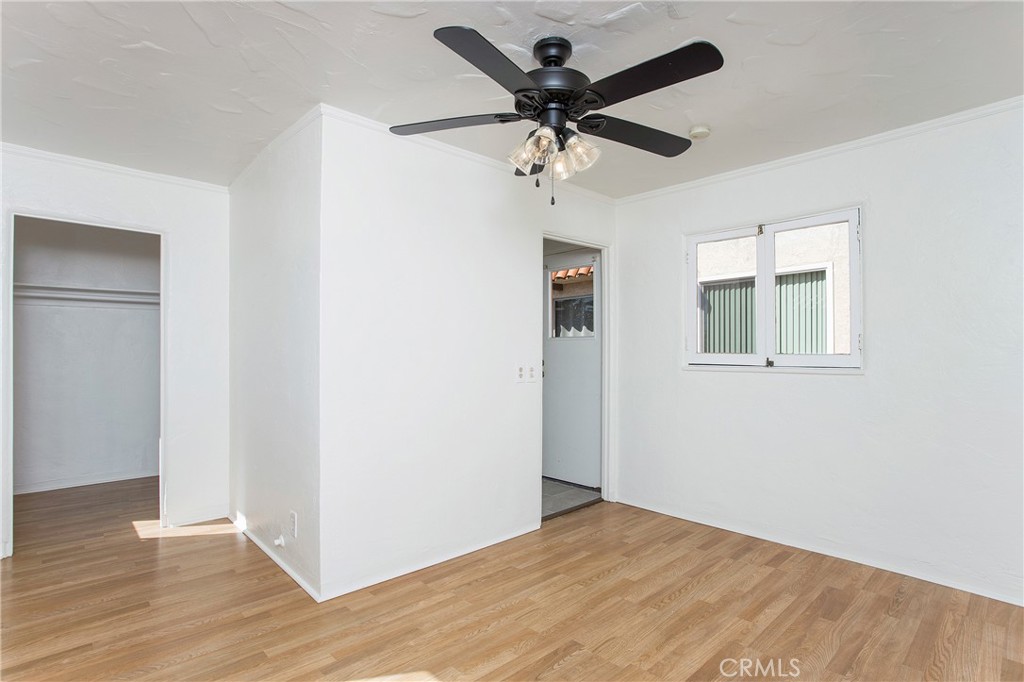 an empty room with wooden floor ceiling fan and windows