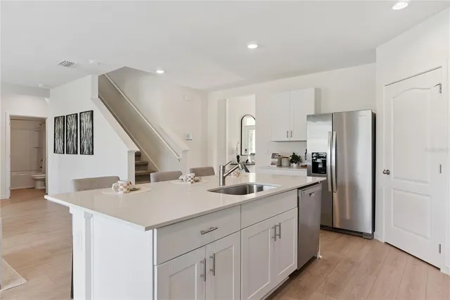 a kitchen with stainless steel appliances a stove a sink a microwave a refrigerator a stove and white cabinets