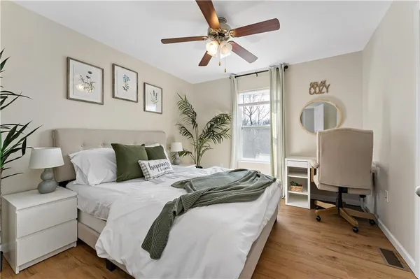 a spacious bedroom with a bed a desk and chair with the potted plant