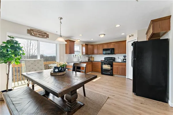 a kitchen with a refrigerator a stove a sink dishwasher and a dining table with wooden floor