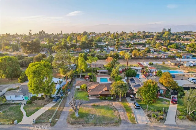 an aerial view of residential houses with outdoor space and trees