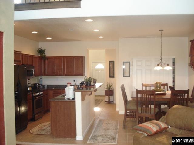 599 Needles Court Reno, NV 89521 - Photo 4 of 13 a kitchen with stainless steel appliances kitchen island granite countertop a table chairs and a living room view