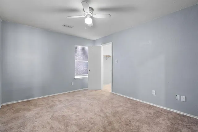en empty room with windows and ceiling fan