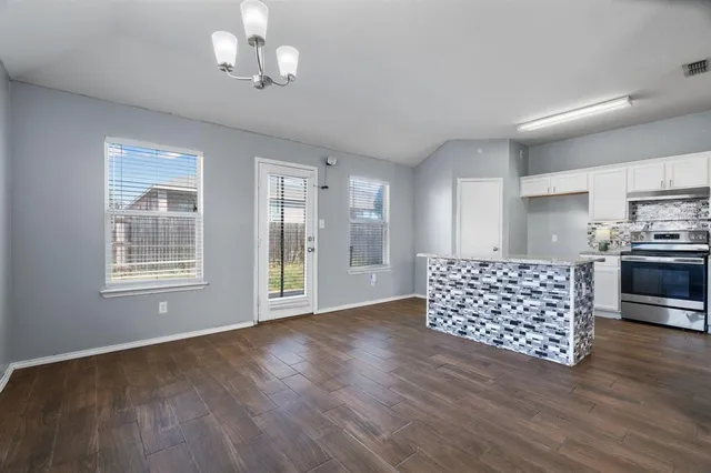 a living room with hard wood floors and kitchen view