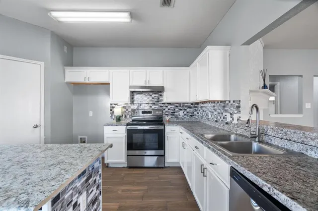 a kitchen with granite countertop stainless steel appliances and white cabinets