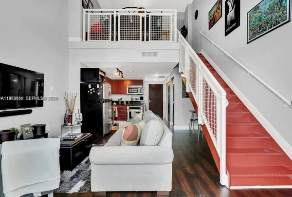a living room with furniture a flat screen tv and kitchen view
