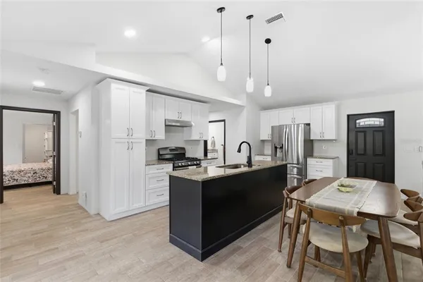a kitchen with stainless steel appliances kitchen island granite countertop a table chairs and a refrigerator