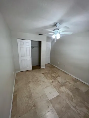 an empty room with chandelier fan and windows