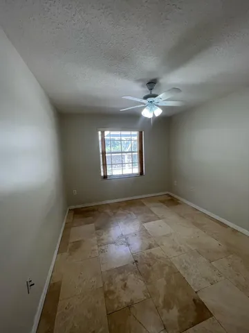an empty room with windows and ceiling fan view
