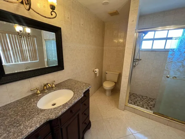 a bathroom with a granite countertop sink toilet and shower