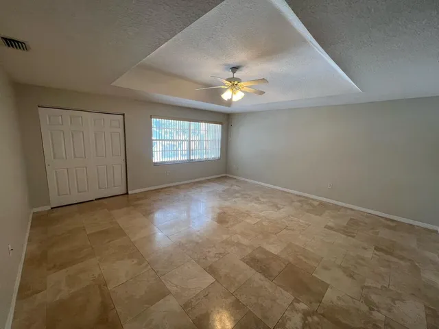 an empty room with windows and chandelier fan