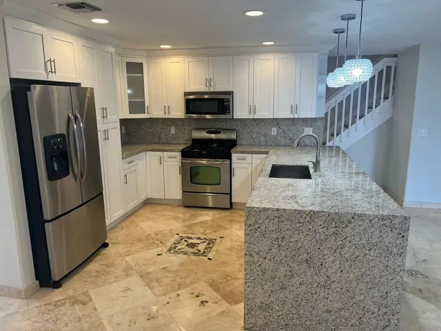 a kitchen with stainless steel appliances granite countertop a refrigerator a stove a sink and a microwave