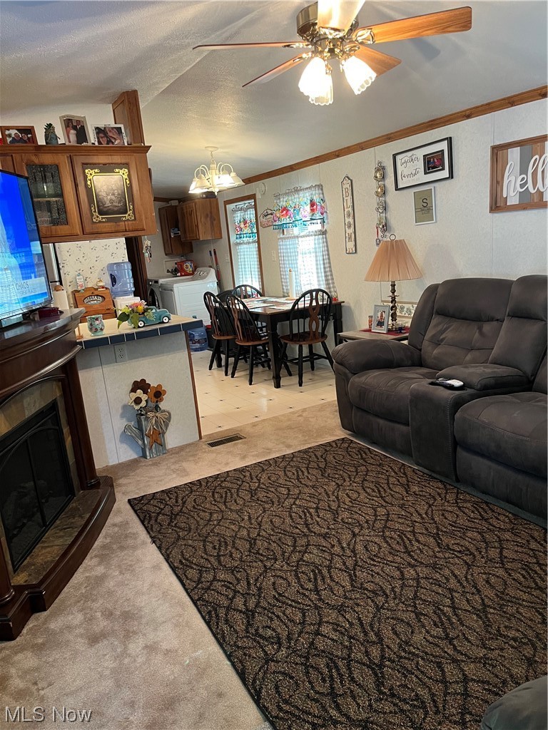 64725 Sundew Road Cambridge, OH 43725 - Photo 24 of 27 Living room with a textured ceiling, light carpet, ceiling fan with notable chandelier, and washing machine and dryer
