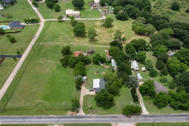 an aerial view of residential houses with outdoor space and trees