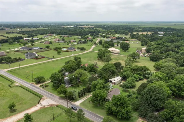 an aerial view of residential houses with outdoor space and trees