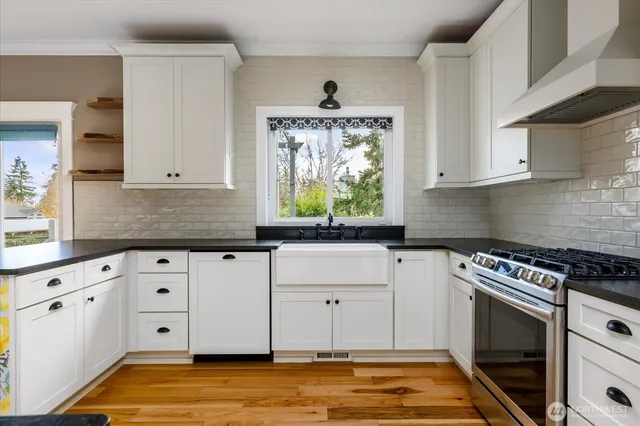 a kitchen with granite countertop a stove a sink and a white cabinets
