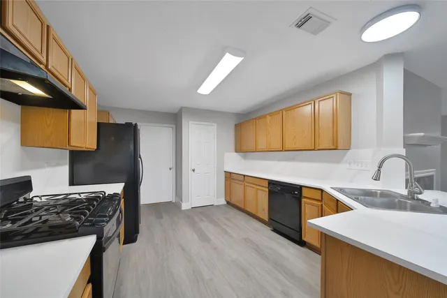 a kitchen with stainless steel appliances granite countertop a refrigerator a sink dishwasher a stove and a sink with wooden floor