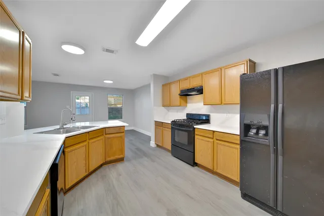 a kitchen with stainless steel appliances granite countertop wooden cabinets a sink and dishwasher with wooden floor