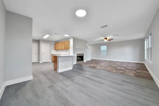 a view of an empty room with wooden floor and windows