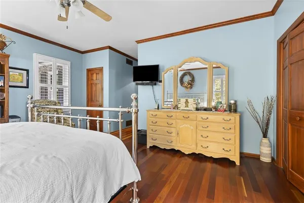 a bedroom with a bed a mirror on dresser and a flat screen tv