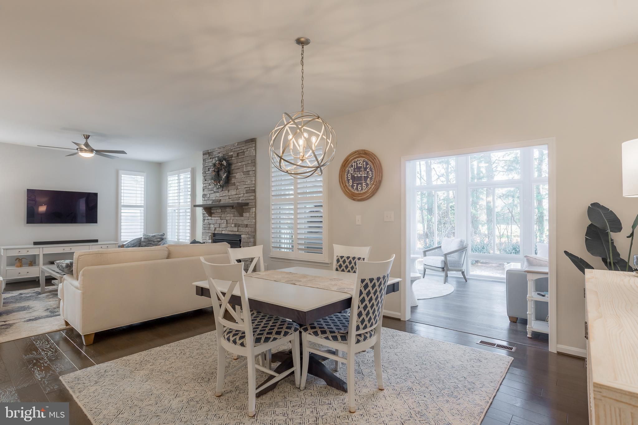 34491 Spring Brook Avenue Lewes, DE 19958 - Photo 16 of 59 a view of a dining room and livingroom with furniture wooden floor a rug a flat screen tv a rug and a chandelier
