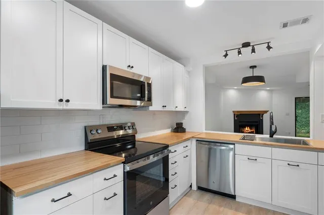 a kitchen with cabinets stainless steel appliances a sink and a window