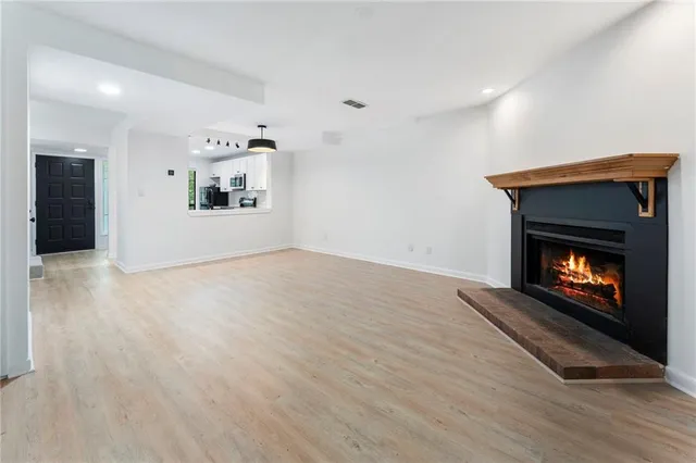 a view of an empty room with wooden floor and a fireplace