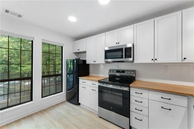 a kitchen with stainless steel appliances white cabinets and a stove top oven