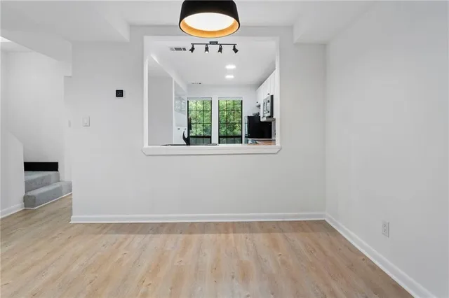 an empty room with wooden floor and windows