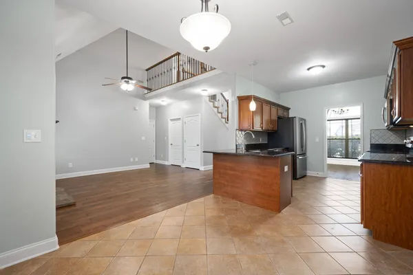 a large kitchen with stainless steel appliances kitchen island granite countertop a refrigerator a stove top oven and a sink with granite countertops