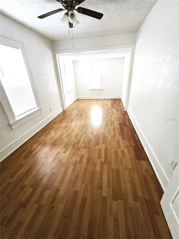 a view of empty room with wooden floor and ceiling fan