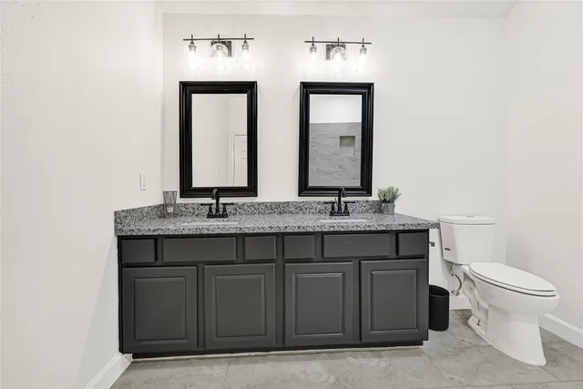 a bathroom with a granite countertop toilet sink and mirror