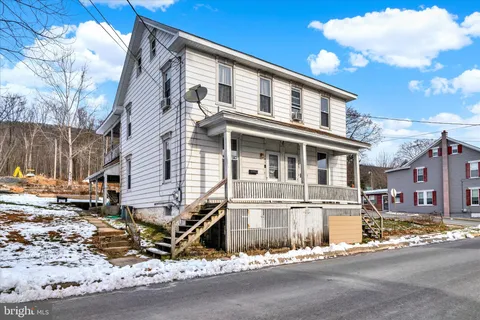 a white building with a large tree in front