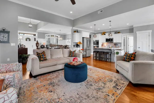 a kitchen with stainless steel appliances kitchen island granite countertop a refrigerator a stove white cabinets and wooden floor