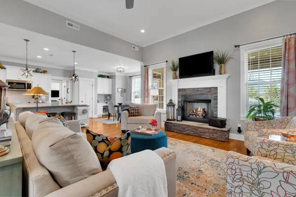 a kitchen with stainless steel appliances granite countertop a stove a refrigerator a kitchen island a dining table and chairs with wooden floor