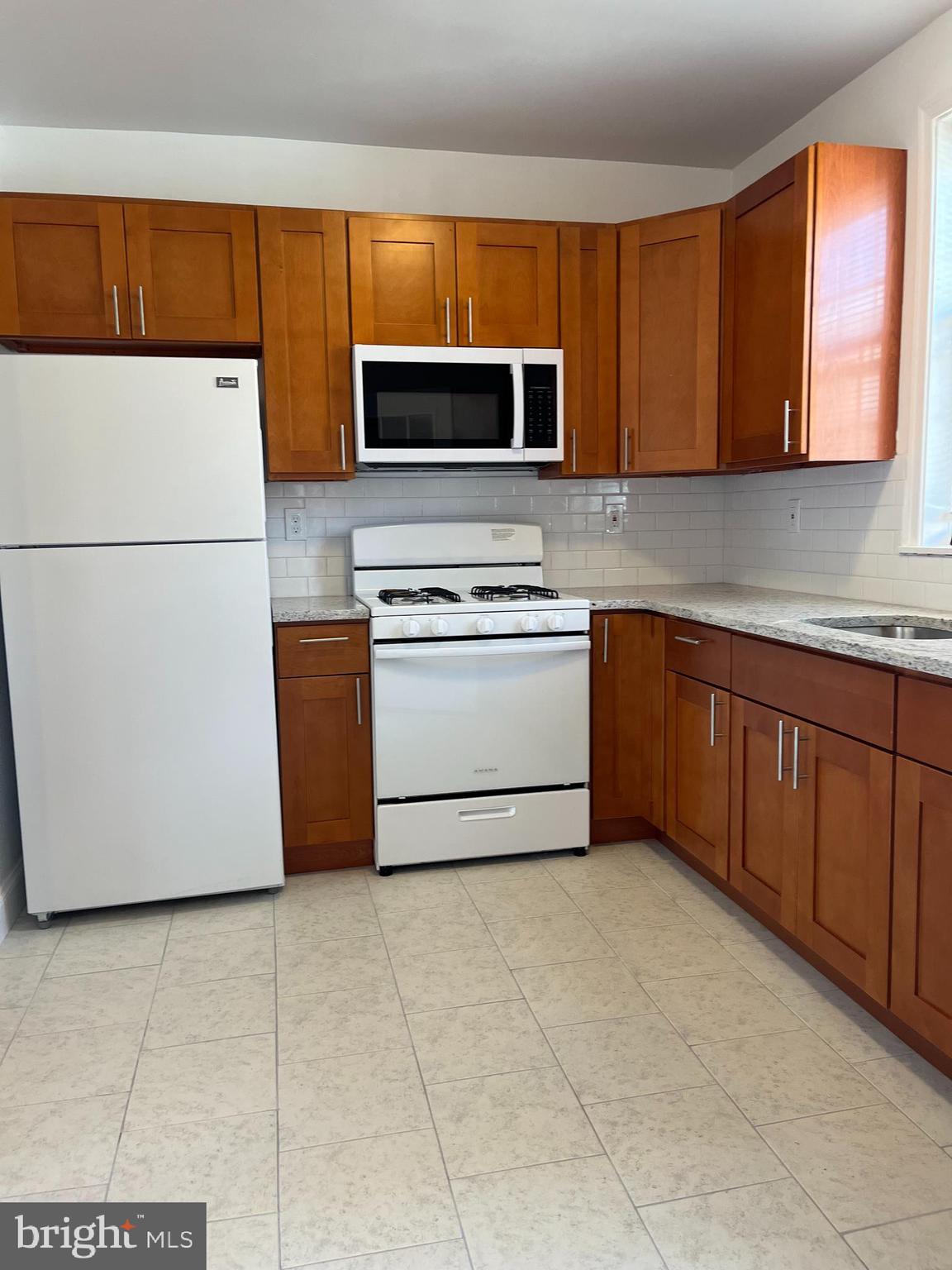 1323 Gilham Street Philadelphia, PA 19111 - Photo 8 of 35 a kitchen with stainless steel appliances granite countertop a stove top oven a sink a microwave and a refrigerator