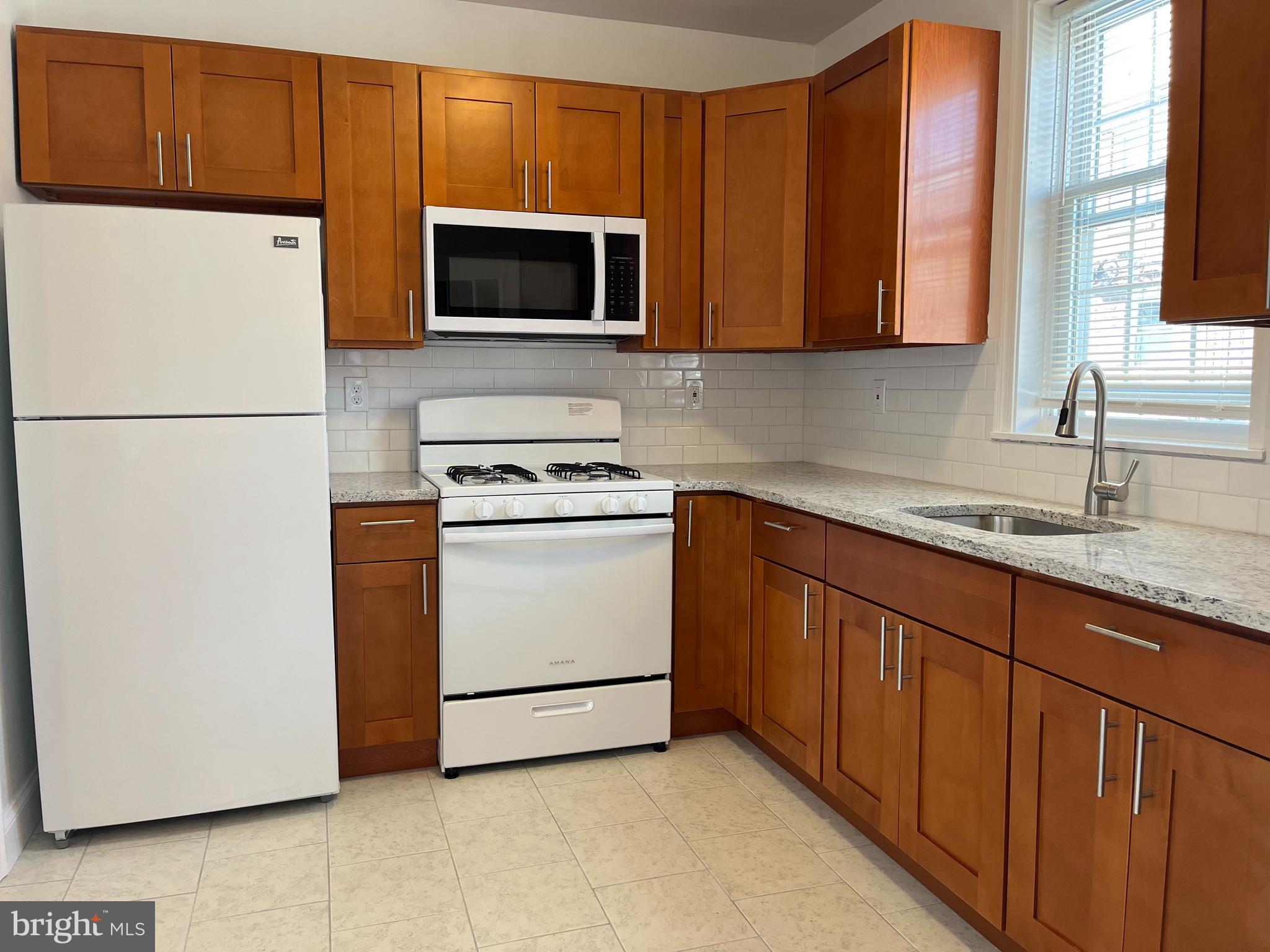 1323 Gilham Street Philadelphia, PA 19111 - Photo 9 of 35 a kitchen with stainless steel appliances granite countertop a refrigerator stove a sink dishwasher and microwave oven