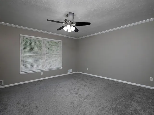 an empty room with windows and fan