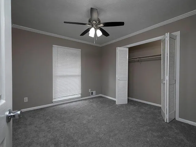 an empty room with closet and a ceiling fan