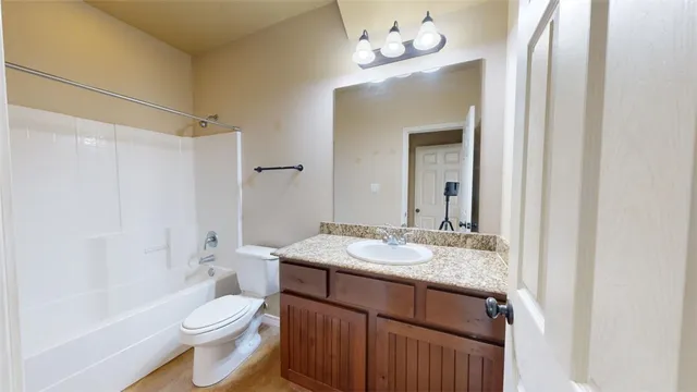 a bathroom with a granite countertop sink toilet a mirror and shower