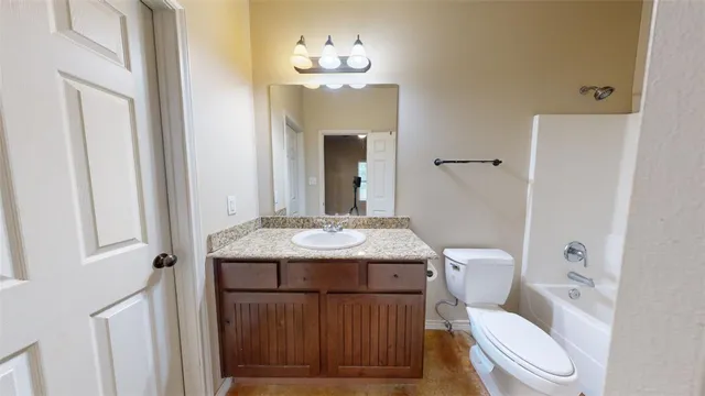 a bathroom with a granite countertop toilet sink and mirror
