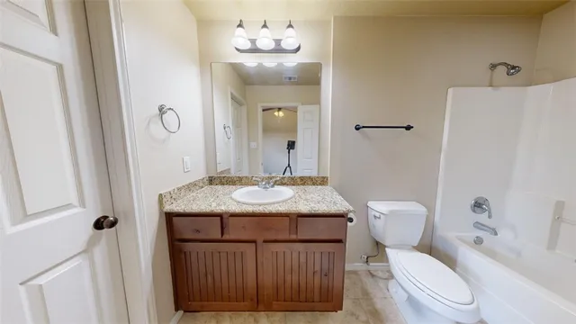 a bathroom with a granite countertop toilet sink and mirror