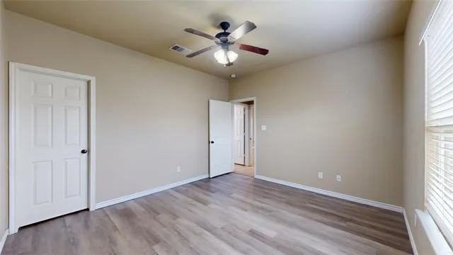 an empty room with wooden floor and ceiling fan