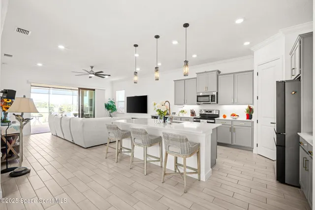 a kitchen with stainless steel appliances kitchen island granite countertop a refrigerator a stove a sink a dining table and chairs with wooden floor