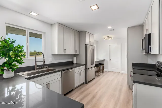 a kitchen with granite countertop a sink stainless steel appliances and cabinets