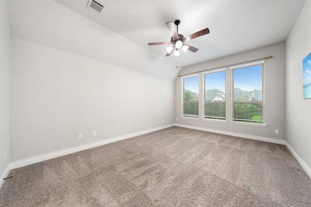 1501 Calcot Lane Forney, TX 75126 - Photo 16 of 34 Spacious room featuring vaulted ceilings, a ceiling fan with light fixture, three large windows with blinds, and neutral carpet flooring