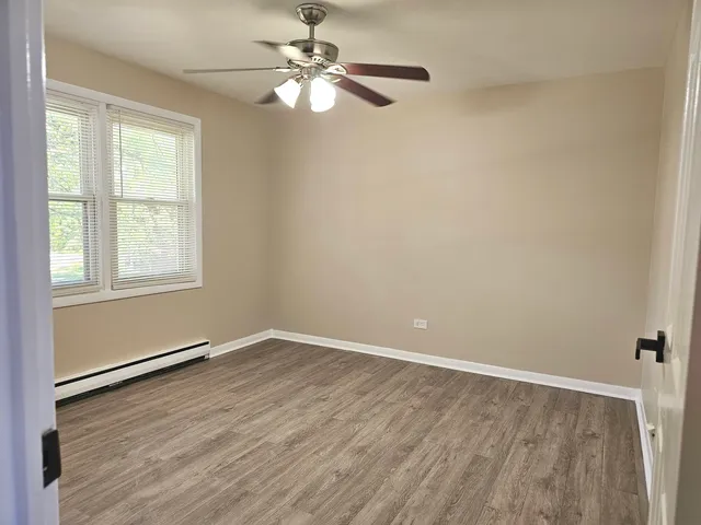 an empty room with wooden floor fan and windows