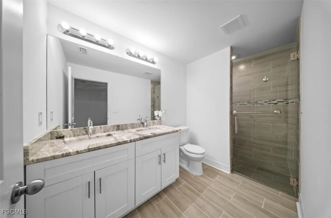 4414 28th Street Southwest Lehigh Acres, FL 33973 - Photo 13 of 29 a bathroom with a granite countertop sink toilet a mirror a vanity and shower