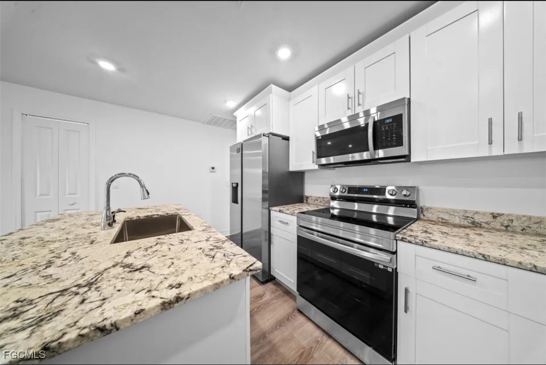 4414 28th Street Southwest Lehigh Acres, FL 33973 - Photo 7 of 29 a kitchen with stainless steel appliances granite countertop a stove a sink and a refrigerator