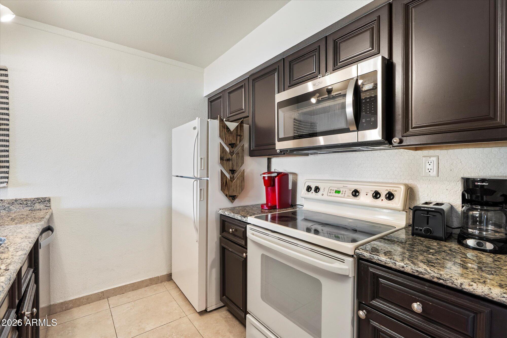 7625 East Camelback Road, Unit B325 Scottsdale, AZ 85251 - Photo 3 of 24 a kitchen with stainless steel appliances granite countertop a stove and a microwave